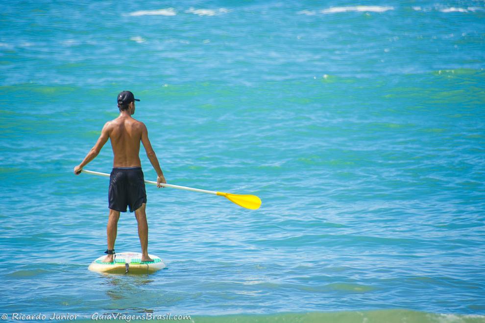 Imagem de um homem praticando standup paddle no mar da Praia do Félix.